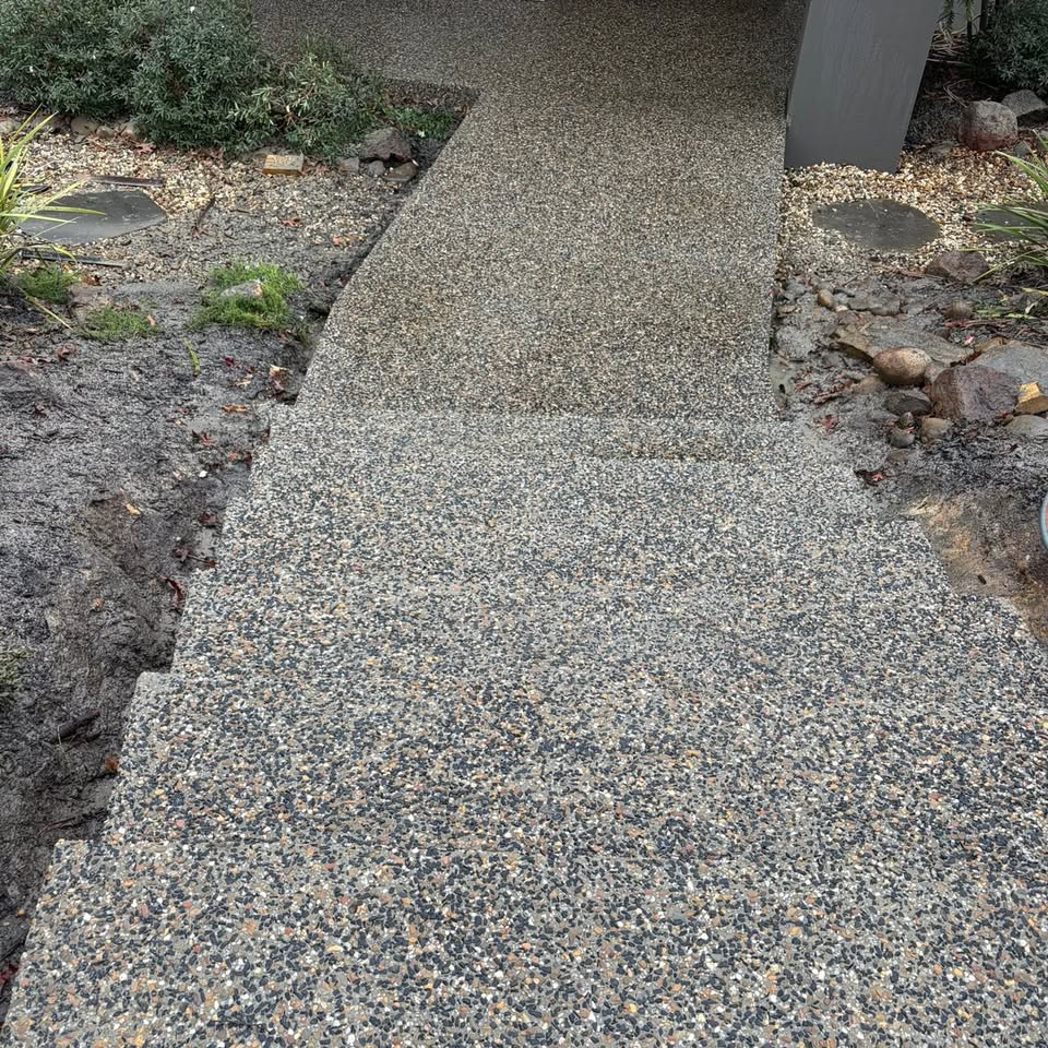 Close-up of an exposed aggregate path finish alongside garden beds